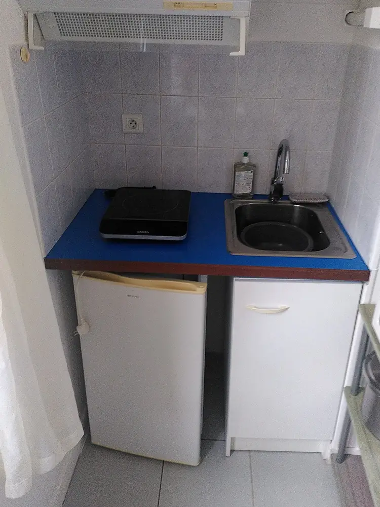 Le plan de travail de la cuisine, issu d'une porte coupe-feu : surface bleue à chant bois, supportant une plaque à induction posable et l'évier.